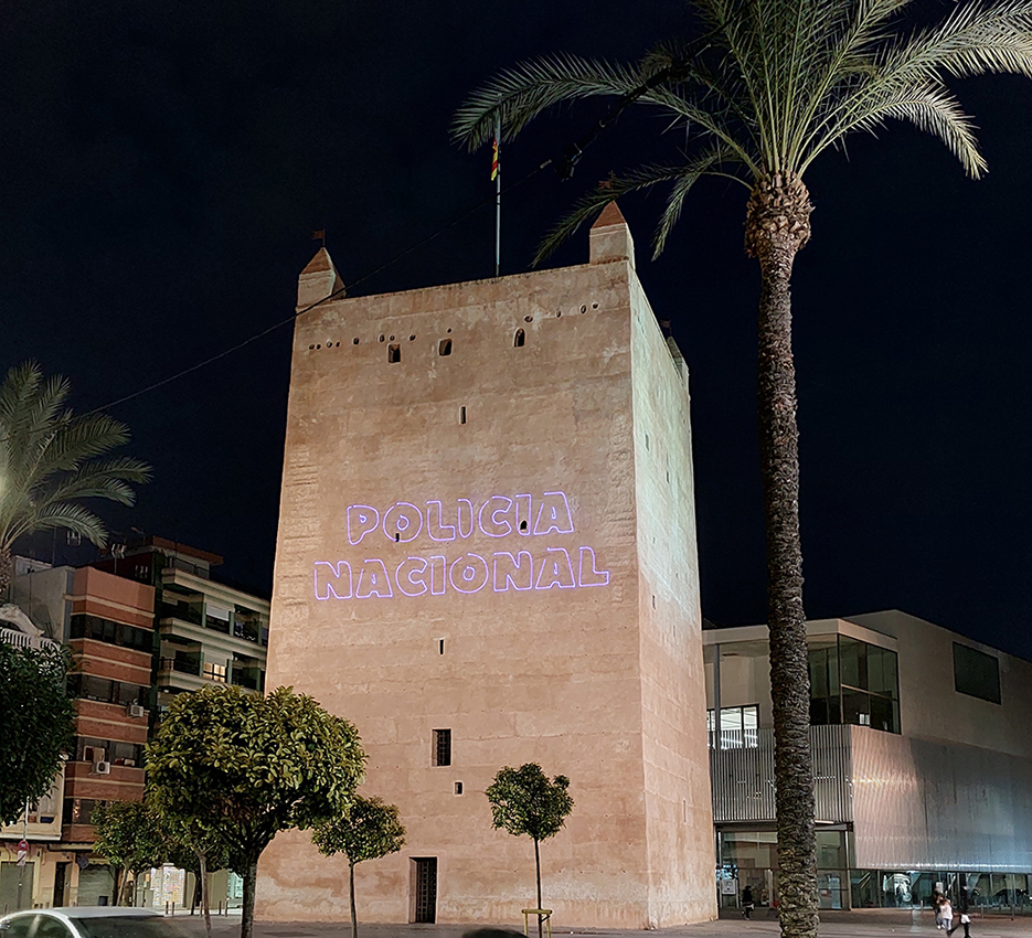 Texto de Policía Nacional iluminado sobre una torre del casco histórico de Torrente. 